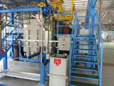 מערך תעשייתי מודרני הכולל ציוד גדול שכותרתו "ELRO". השטח כולל מיכלים, לוחות בקרה, מדרגות מתכת ומעקות בטיחות. תאורה עילית מאירה את החלל, והרצפה נקייה עם שבילים מסומנים לניווט בטוח.